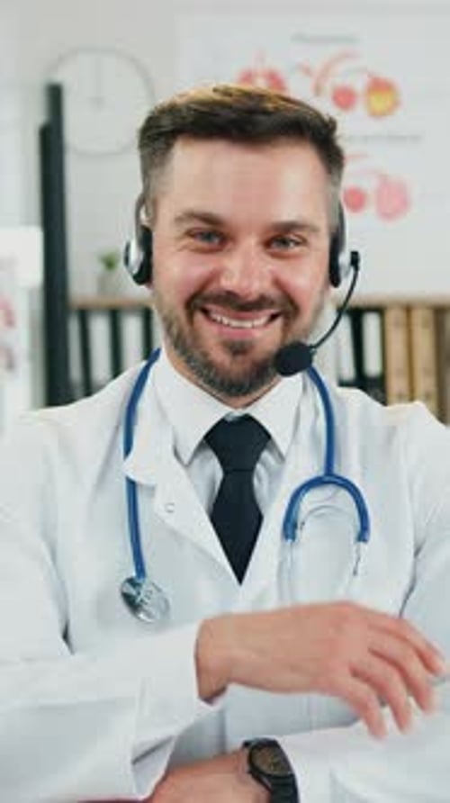Goodlooking Smiling Man Doctor in Wireless Headphones Posing on Camera in Clinic Lab Nearby African