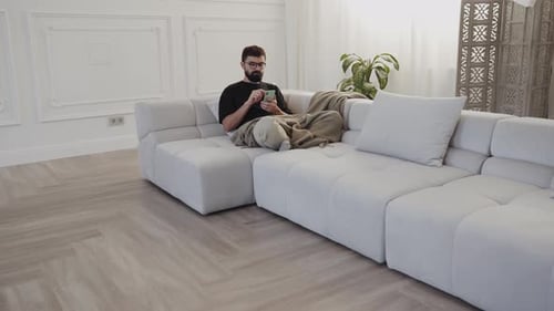 Man Relaxing on Couch Using Smartphone