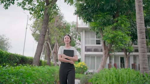 Woman Holding Tablet Walking in Garden