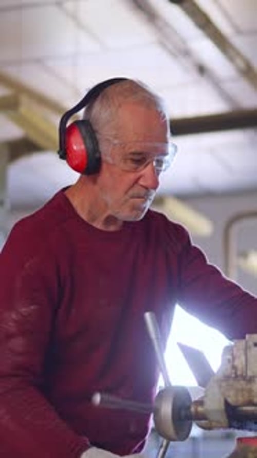 Senior Man Using Lathe in Workshop with Safety Gear