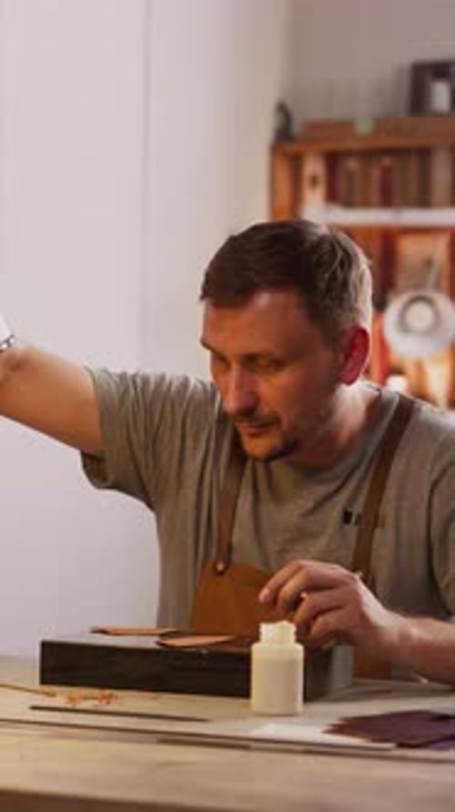 Man Adjusts Tischlampe für eine komfortable Lederverarbeitung