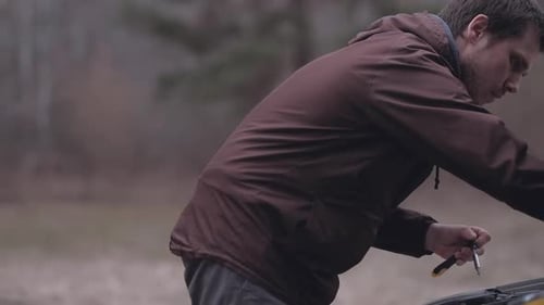 Man Repairs Car Engine in Rural Area