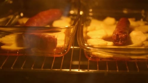 Sausages and Potatoes Cooking in Oven Dishes