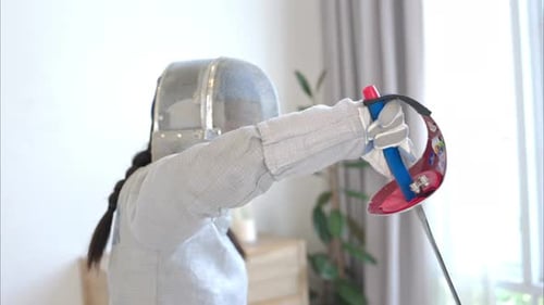 Before the tournament day, a boy and girl dressed in fencing gear are rehearsing in gym