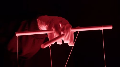 The Puppeteer Controls the Puppets in the Theater in Red Neon Light Closeup Managing People at Work