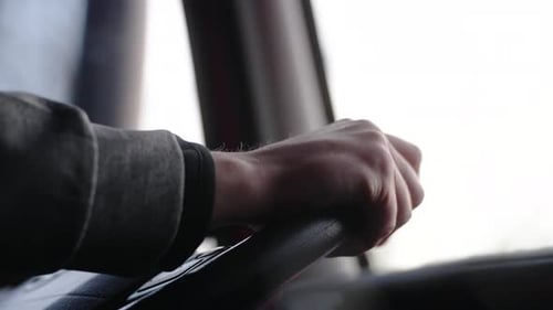 extreme close up of hands on steering wheel driving forward a semi truck. shallow depth of field