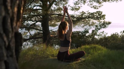 Caucasian girl namaste yoga pose in forest at morning summer sunrise