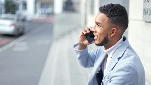 Stylish and successful businessman talking on a phone while waiting and checking the time