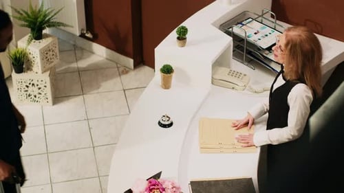 Receptionist Helping Guest at Hotel Reception Desk
