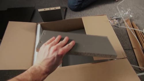 Un homme filme l'assemblage d'un tiroir Flatpack avec son partenaire sur un caméscope