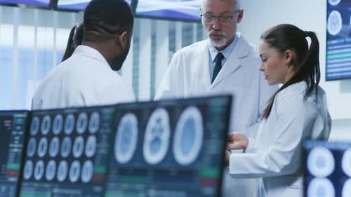 Computer Screen Showing MRI, CT Image Scans of the Brain. In the Background Meeting of the Team of