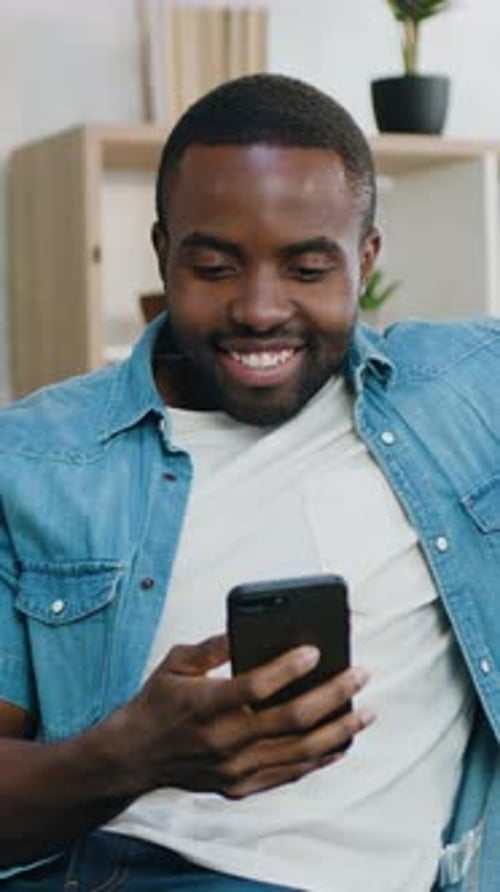 Smiling Man Using Smartphone Indoors