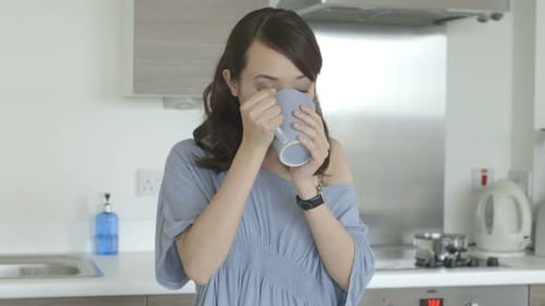Woman Enjoying Warm Drink in Modern Kitchen