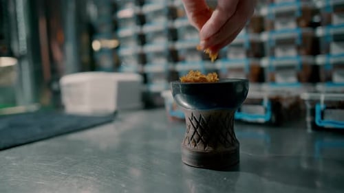 Hands Filling Hookah Bowl with Flavored Tobacco