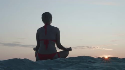 Woman in bikini on the beach meditating at sunset. Timelapse 4k video.