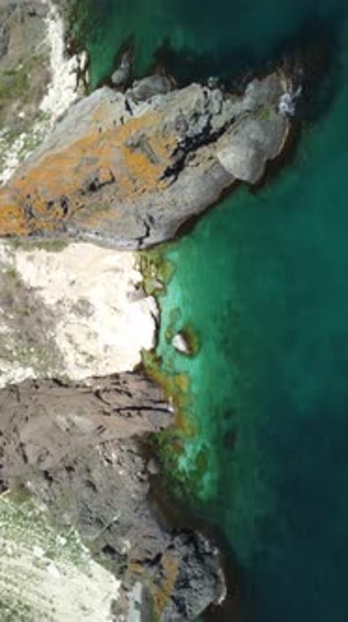 Vertical Aerial View on Calm Azure Sea and Volcanic Rocky Shores Small Waves on Water Surface in