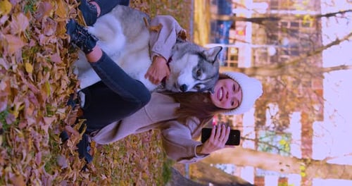 Woman With Husky Dog Taking Selfie in Fall Park