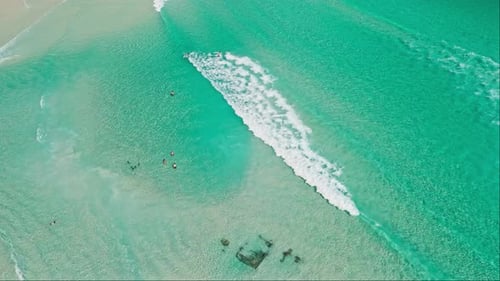 Aerial drone view of turquoise sea water with white foaming wave on Arraial Do Cabo beach, Rio de Ja