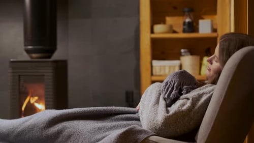 Woman Resting Peacefully in Chair by Fireplace