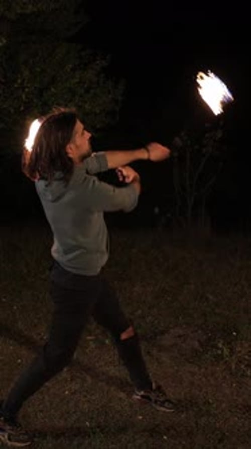 Man Fire Dancing with Burning Batons at Night