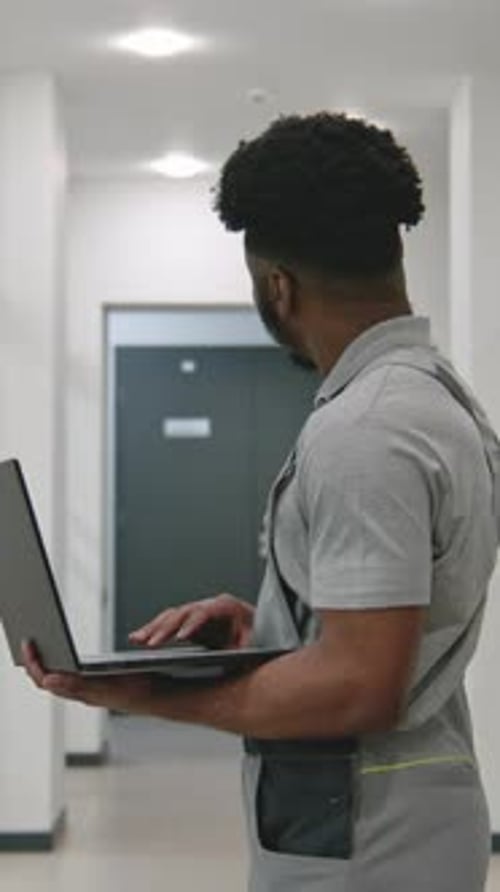 Young Man Using Laptop in Bright Hallway