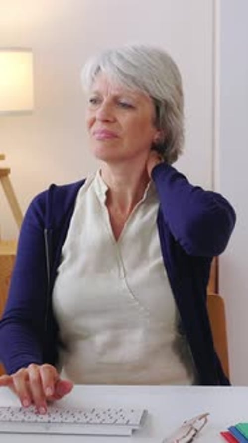 Middle Age Businesswoman with Neckache Sitting at Desk at Home Office