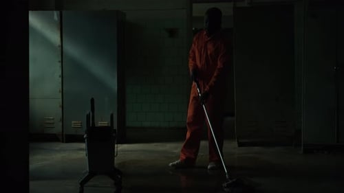 Inmate Cleaning Floor in Dark Prison Room