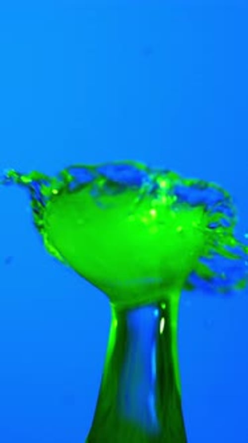 Dramatic Green Water Collision And Droplet Against Bright Blue Background