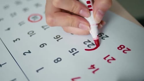 Hand Circles Date on Calendar with Red Marker