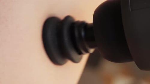 Person massaging triceps with percussion massager. Joint pain relief therapy and muscles.