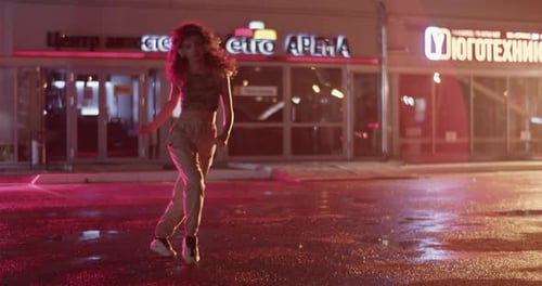 Young Woman Dancing Outside Mall at Rainy Night