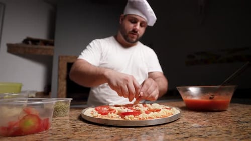 Koch bereitet eine Frischtomaten-Käsepizza mit Champignons zu