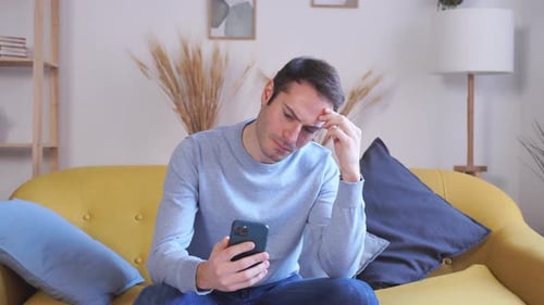 Man Using Smartphone on Couch at Home