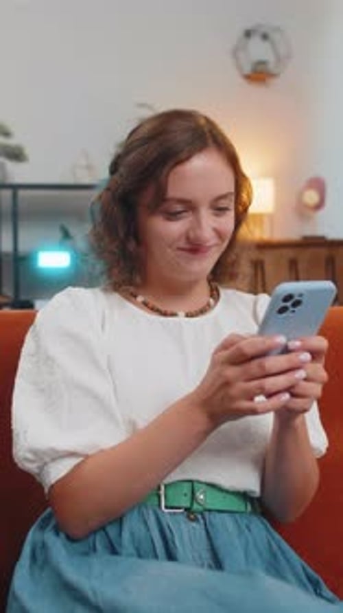 Woman Using Mobile Phone Smiling in Home Interior