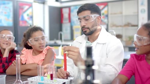 In a school classroom, a biracial teacher demonstrates a science experiment