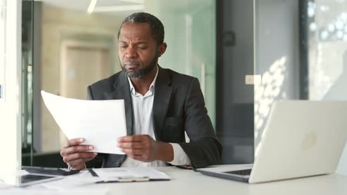 Excited Businessman Reviews Documents, Celebrates Success