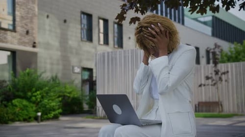 Businesswoman Sitting With Laptop Holding Head in Hands