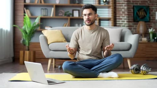 Man on Yoga Mat Talking to Laptop