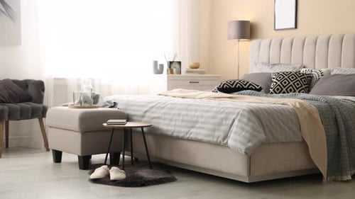 Comfortable bed with soft linens and blankets in room, camera moving right. Home textile