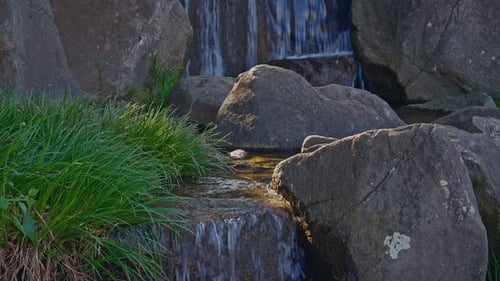 Kleiner Wasserfall, der über Felsen im japanischen Garten kaskadiert