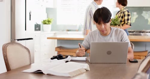 Young Adult Studying at Dining Table with Laptop