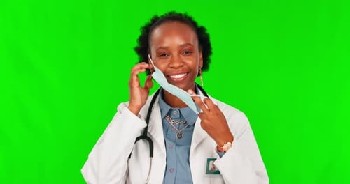 Thumbs up, mask and a doctor black woman on green screen background in studio for healthcare