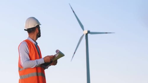 Reading the documents. Service engineer is on the field with windmills