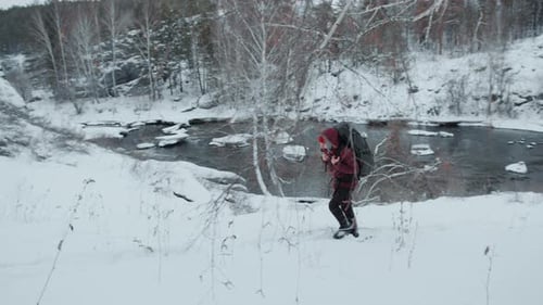 Hiker with Backpack Walking Through Snowy Wilderness