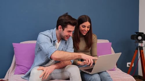Young Couple Smiling Using Laptop on Sofa