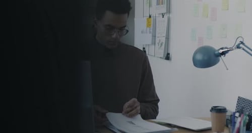 Portrait of Young Specialist Dealing with Papers Working at Desk in Modern Glass Wall Office