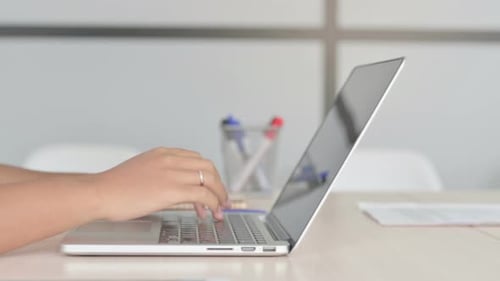 Side View of African Woman Typing on Laptop Keyboard