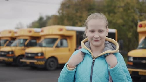 Portrait of a Female Pupil Against the Background of a Typical Yellow School Bus