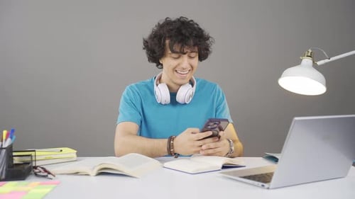 Student Studying with Books, Laptop, and Smartphone