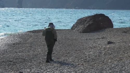 Beach MetalDetecting Detectorist Man Searches Pebbles at Seaside for Treasure in Daytime Near Sea